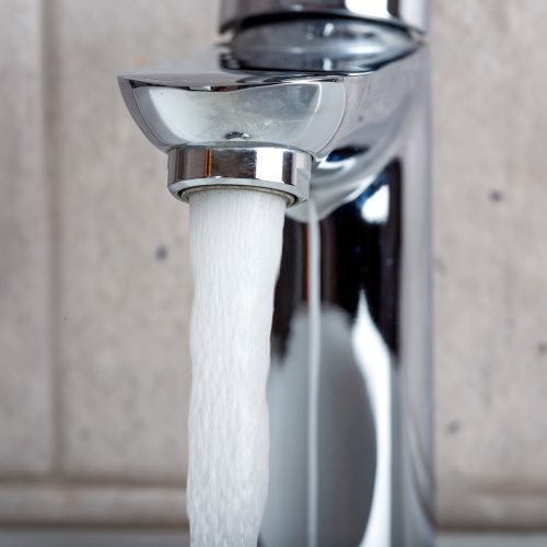 Flowing water from a modern designer chrome water tap